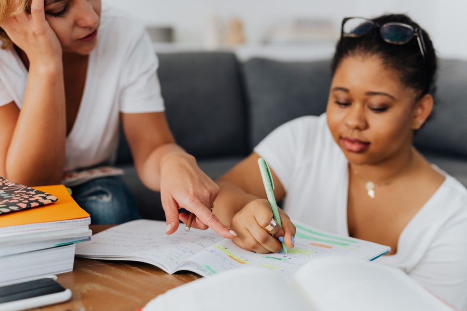 A tutor pointing out a correction in a student's notebook