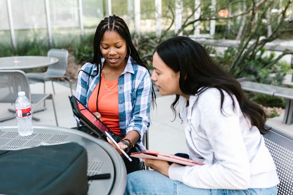 Two students reviewing a tablet at an outdoor table