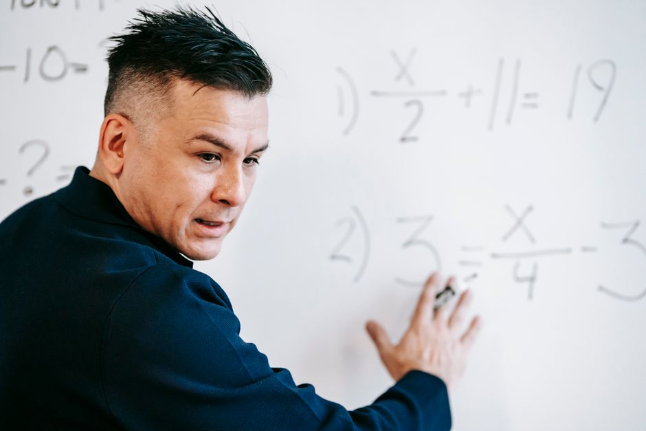 A tutor explaining an algebra problem on a whiteboard